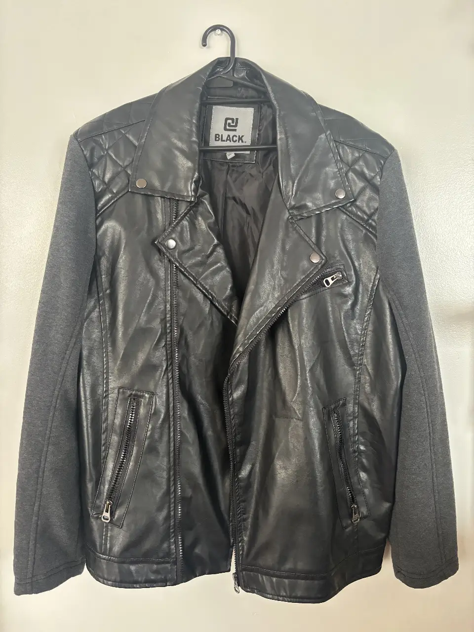 Campera de hombre estilo biker, con mangas grises y cuerpo negro. Detalles de costuras en los hombros y cierre asimétrico. Ideal para un look rocker y casual. Mangas no son de cuero.
