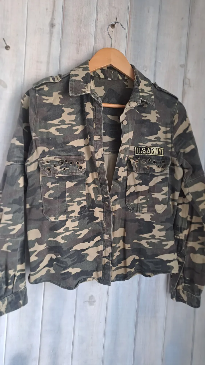 Campera de jean camuflada con parche U.S.ARMY. Ideal para un look urbano y canchero. Bolsillos delanteros y detalles de ojales.