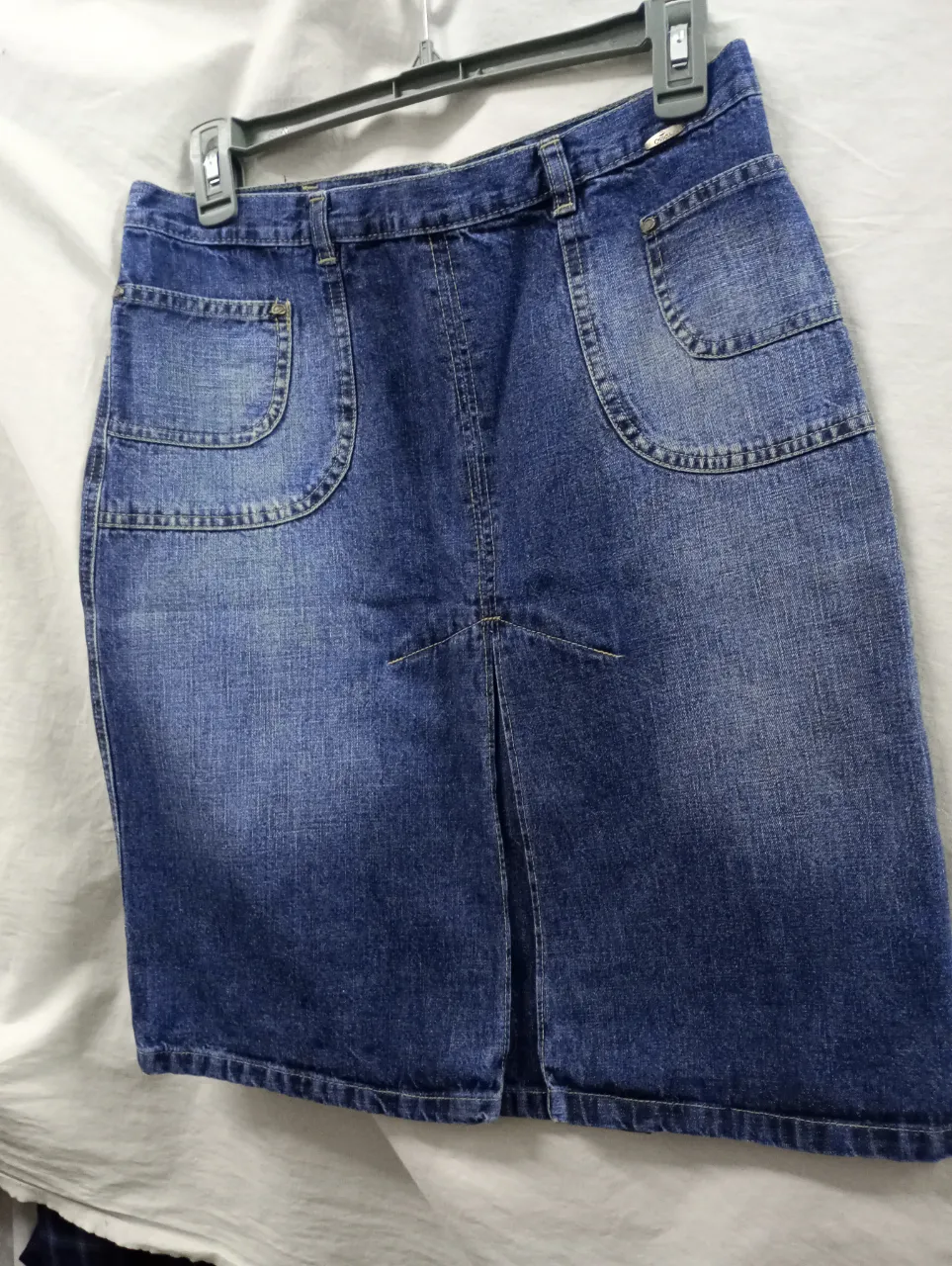 Pollera de jean azul con bolsillos delanteros y traseros. Tiene una abertura en la parte delantera.