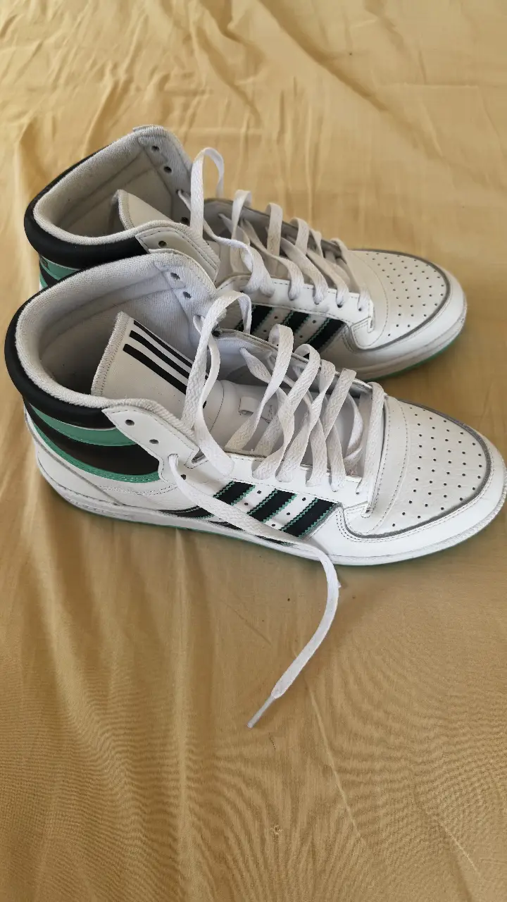 Zapatillas Adidas Top Ten Hi, blancas con detalles en negro y verde. Diseño clásico de caña alta, ideales para un look urbano y deportivo.