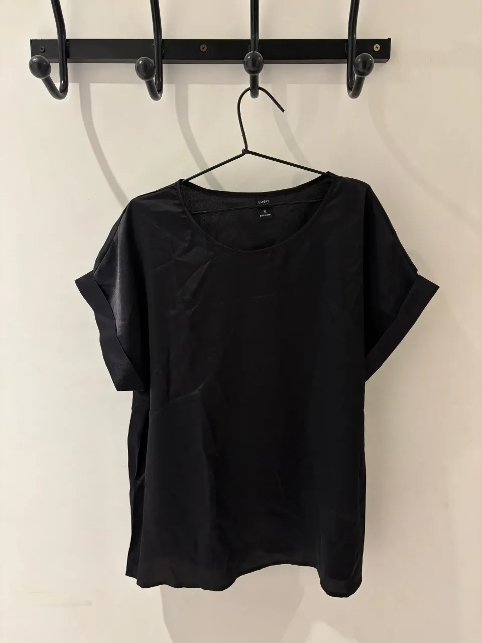 Remera negra de seda, con mangas cortas dobladas y cuello redondo. Ideal para un look elegante y moderno.