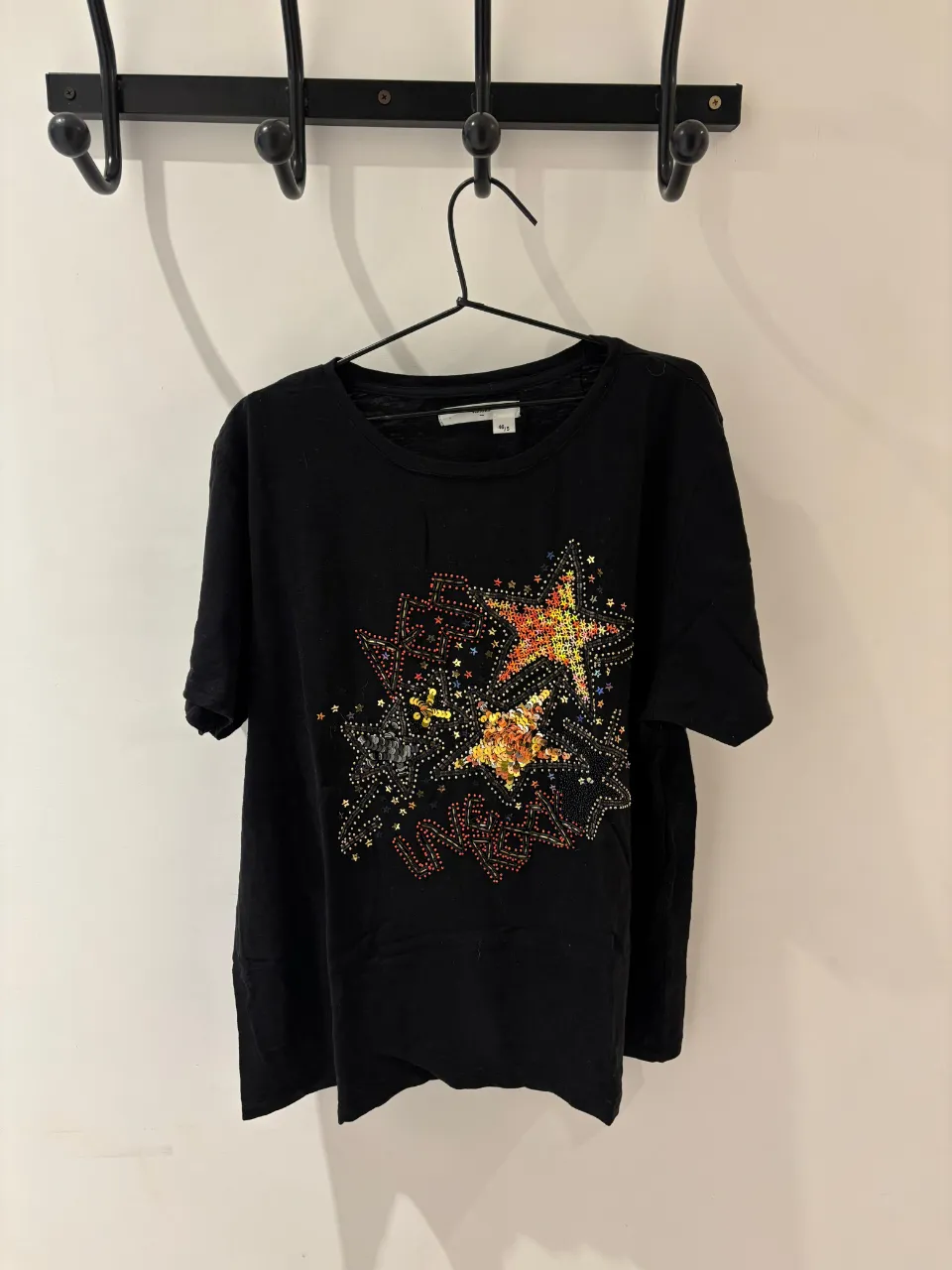 Remera negra con un estampado de estrellas y detalles brillantes en la parte delantera. Ideal para un look casual y canchero.