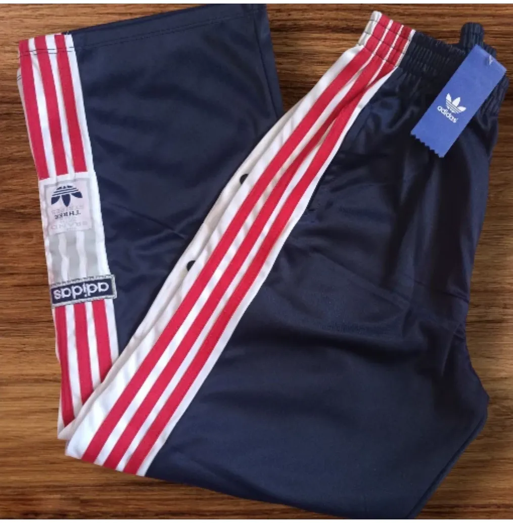 Pantalón deportivo Adidas con las clásicas tres tiras en rojo y blanco en los laterales. Ideal para un look retro y cómodo. Con etiqueta.