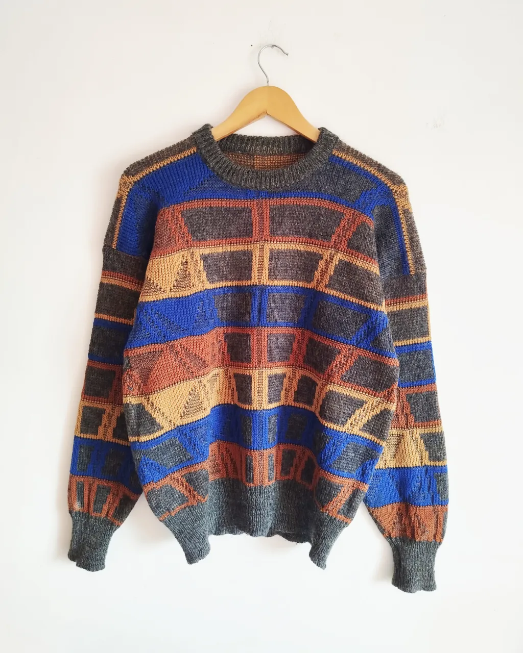 Sweater de tejido de punto con cuello redondo y mangas largas. Presenta un diseño de rombos y líneas en tonos grises, azules, terracota y amarillos. 
Medidas .
Hombros 58cm( cae mas abajo del hombro)
Axila a axila 51cm
Sisa 27cm
Largo de mangas (cuello a puño) 74cm
Largo 65cm