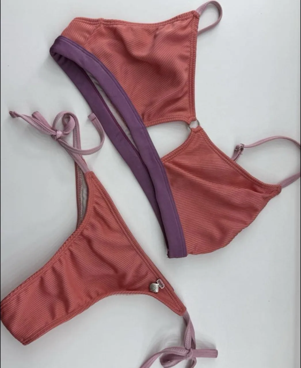 Conjunto de bikini de dos piezas, corpiño con aro y detalles cut-out, y bombacha colaless con tiras regulables. Diseño acanalado en tono salmón y detalles en lila. Ideal para lucir en la playa o la pileta. Bombacha S y  Corpiño L