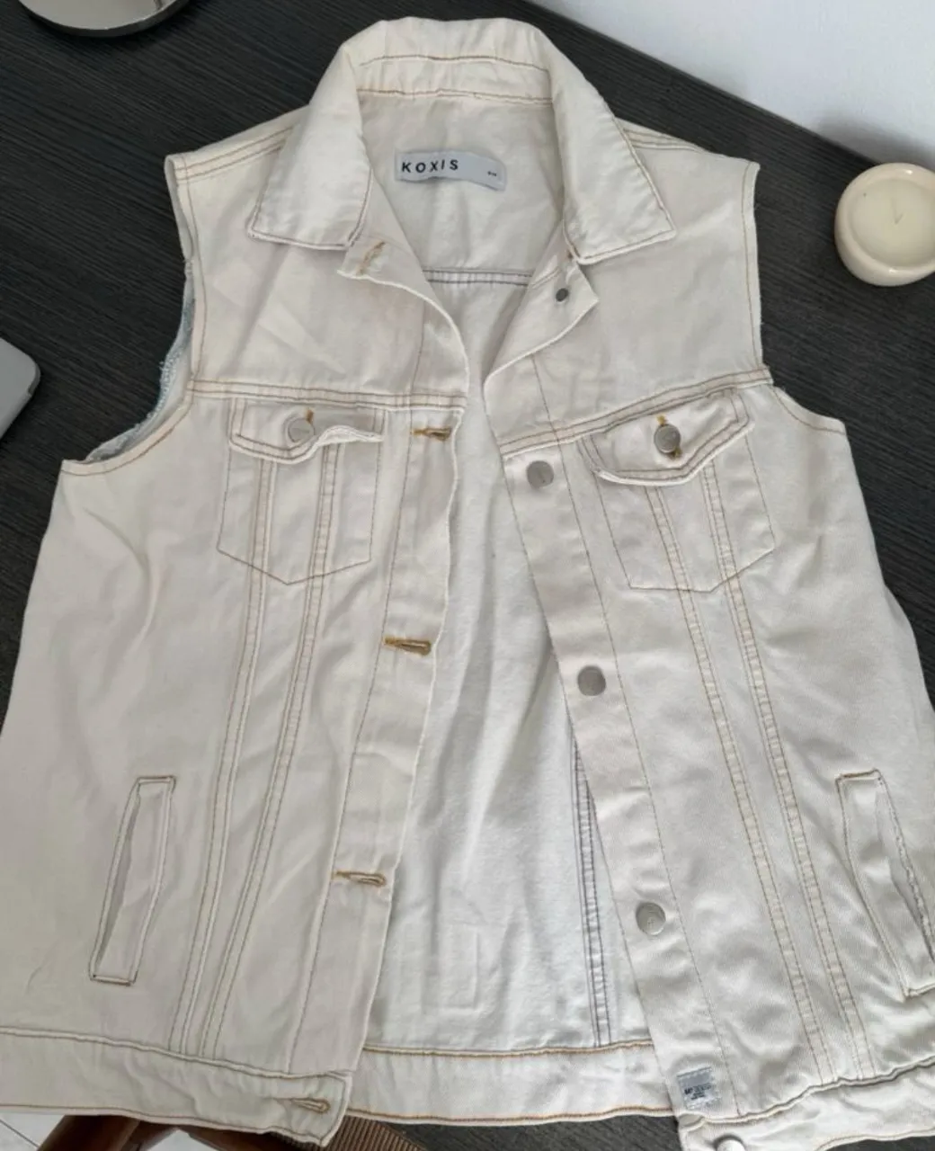 Chaleco de jean blanco con costuras en crudo, ideal para un look canchero y moderno. Perfecto para combinar con remeras básicas o estampadas, dándole un toque único a tu outfit. Largo.