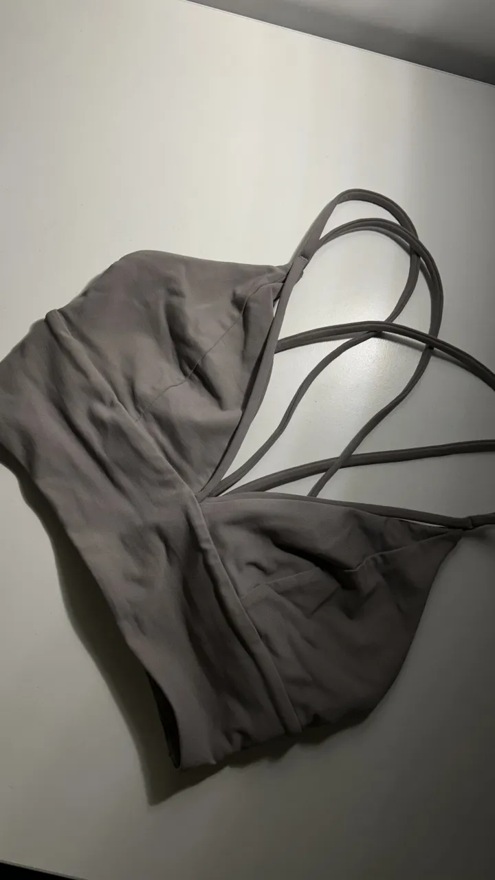 Top deportivo gris con tiras cruzadas en la espalda. 