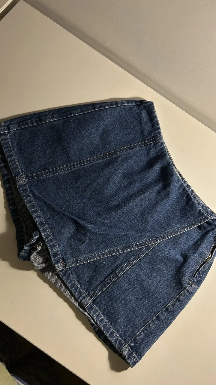 Short pollera de jean tiro alto con diseño de recortes y cierre lateral. 