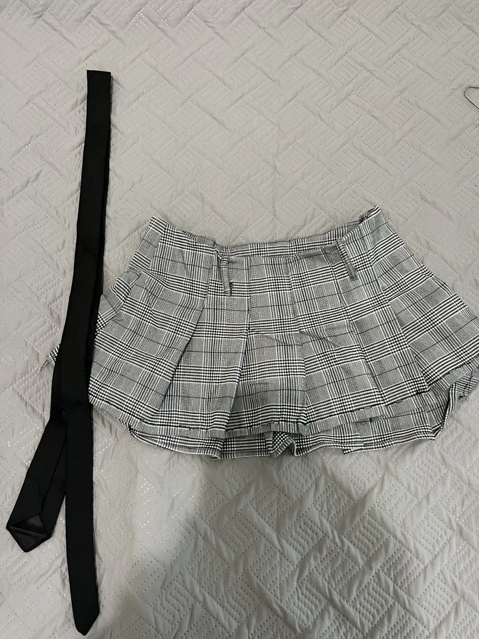 Pollera corta a cuadros escoceses, con tablas y detalle de lazo negro. Ideal para un look colegiala o Y2K.