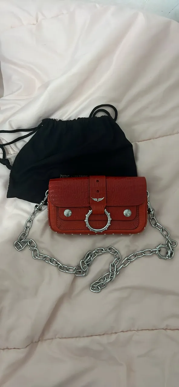 Cartera Zadig & Voltaire roja de cuero con detalles plateados y cadena. Incluye bolsa protectora con logo de la marca y dedicatoria en el interior.