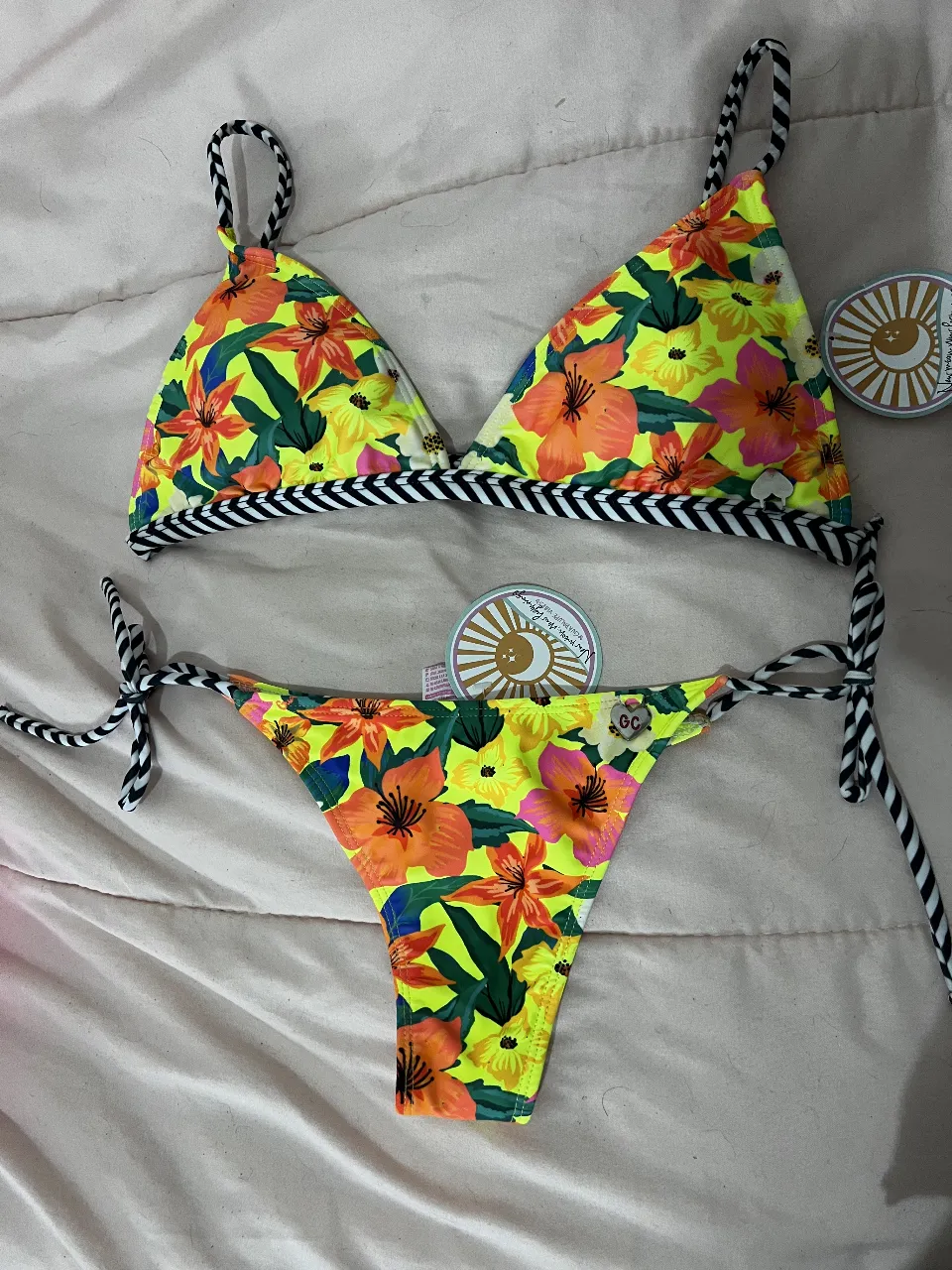 Conjunto de bikini Guadalupe Cid con estampado floral en tonos amarillos y naranjas. Incluye corpiño triangular con detalles en negro y blanco talle 4 y bombacha con tiras ajustables talle 1. Ideal para la playa o pileta.