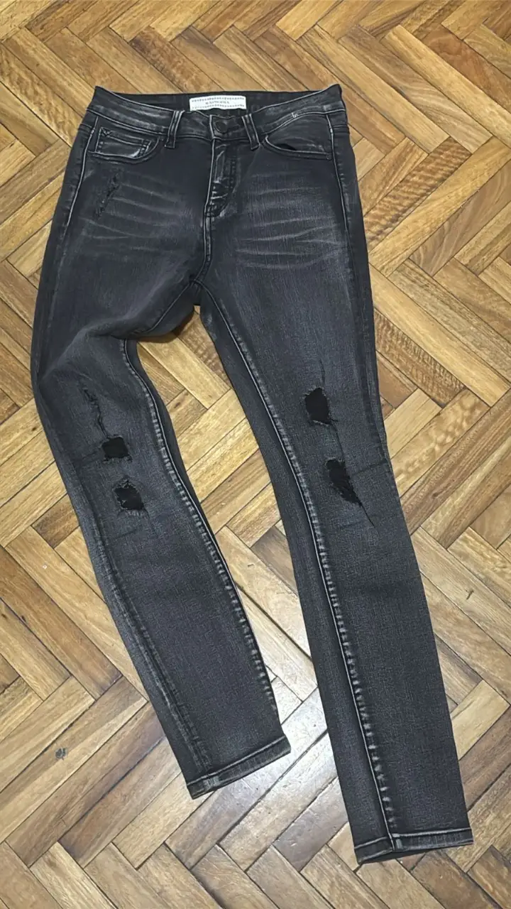Jeans de mujer negros con roturas. Tiro medio y calce skinny. Marca Rapsodia. Talle 26.