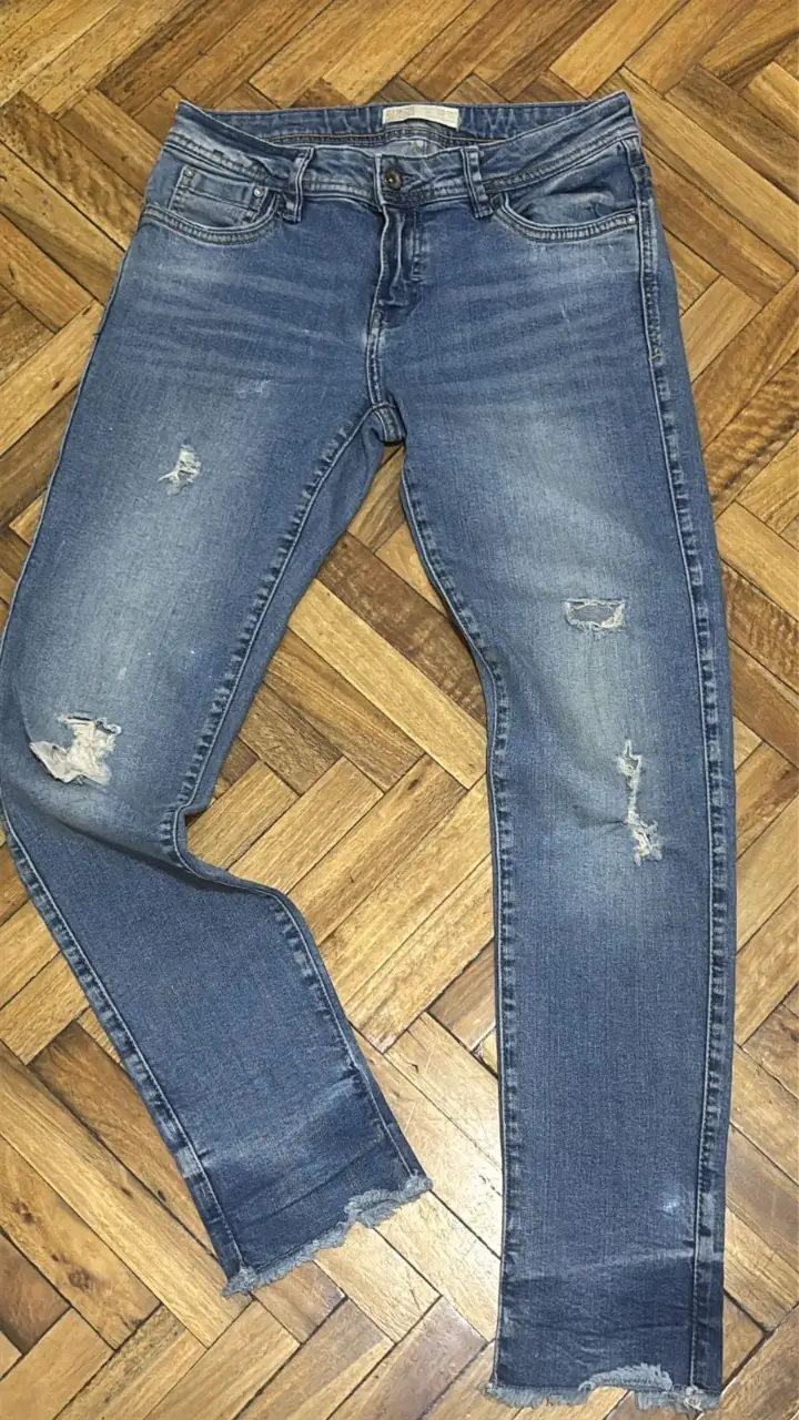 Jeans de hombre, azul gastado con roturas en las rodillas. Tiro medio y corte recto. Ideal para un look casual y moderno.