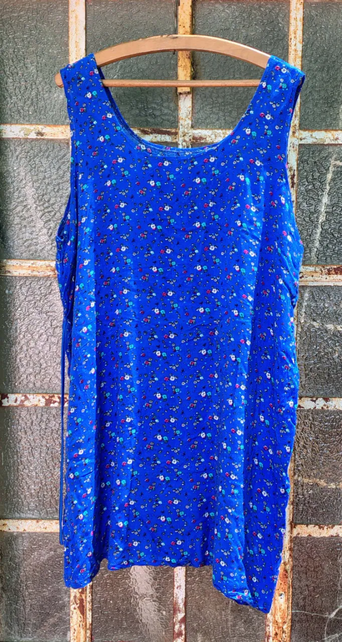 Vestido azul con estampa de flores pequeñas en varios colores. Posee tiras para atar en la espalda.