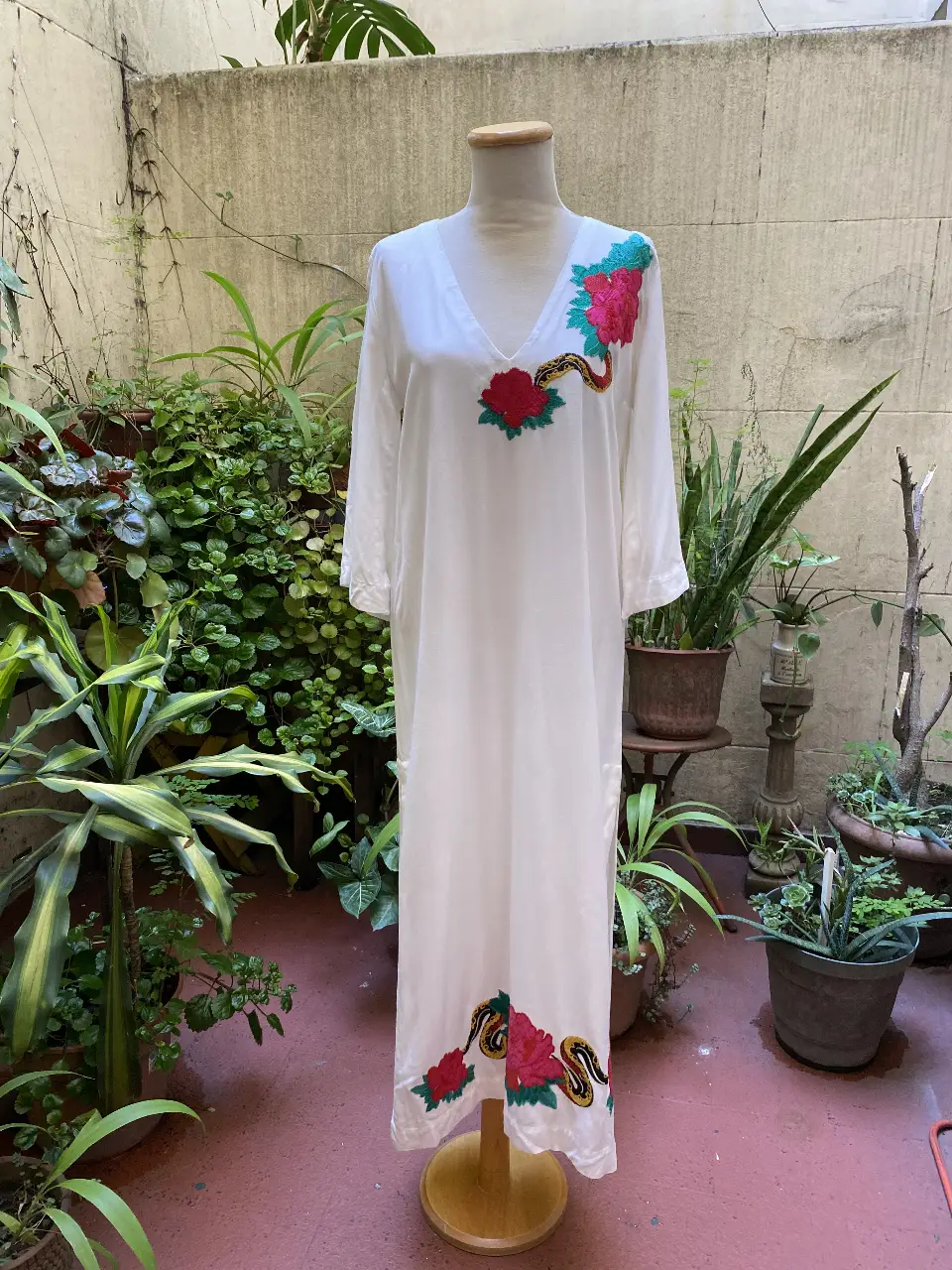 Vestido largo blanco con bordados florales en rojo y detalles en amarillo y verde. Ideal para un look bohemio y fresco.