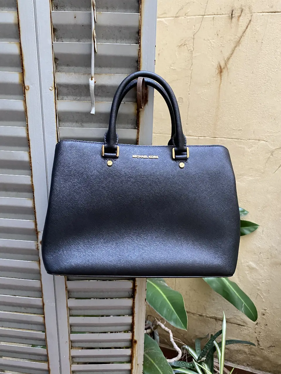 Cartera Michael Kors negra, con manijas y correa para colgar. Ideal para llevar todo lo necesario con estilo.