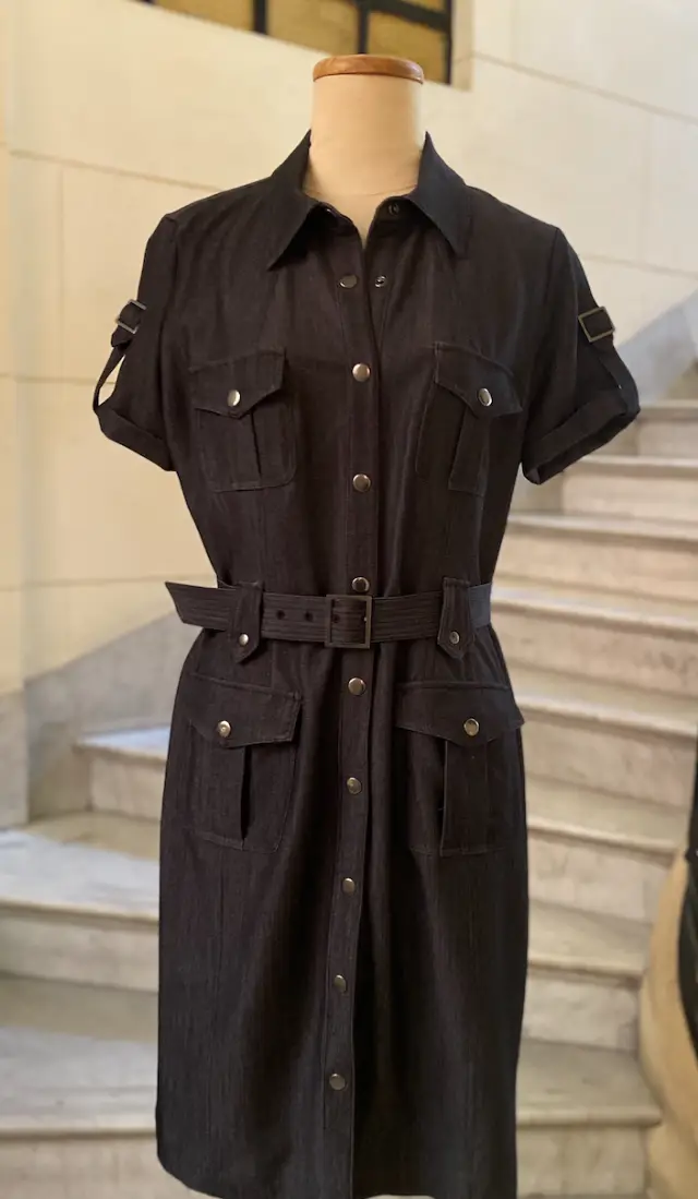 Vestido midi de jean negro con botones y cinturón. Estilo utilitario con bolsillos y detalles de hebillas en las mangas.