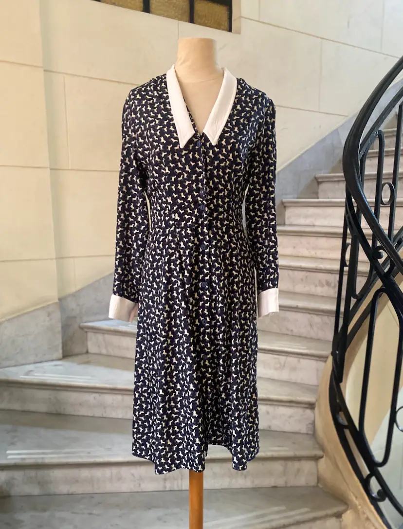 Vestido midi vintage con estampado de figuras en azul marino y blanco. Cuello camisero blanco y puños blancos. Ideal para un look elegante y retro.