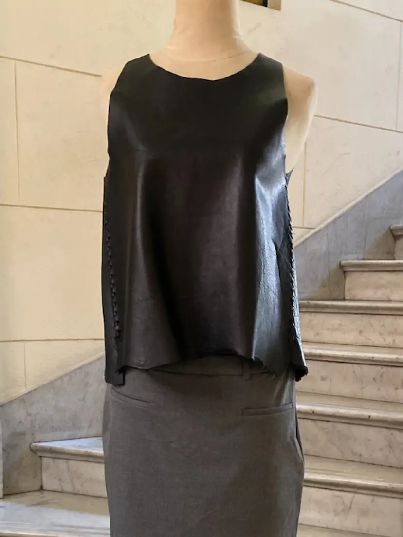 Top negro de cuero sintético, sin mangas, ideal para un look moderno y audaz. Perfecto para combinar con pantalones de vestir o jeans.