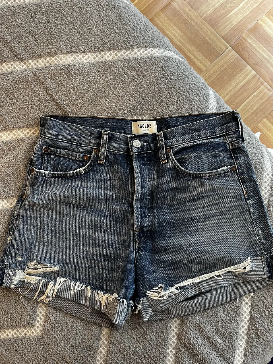 Short de jean de mujer, con detalles de roturas y flecos en el borde. Marca AGOLDE, talle 27.
