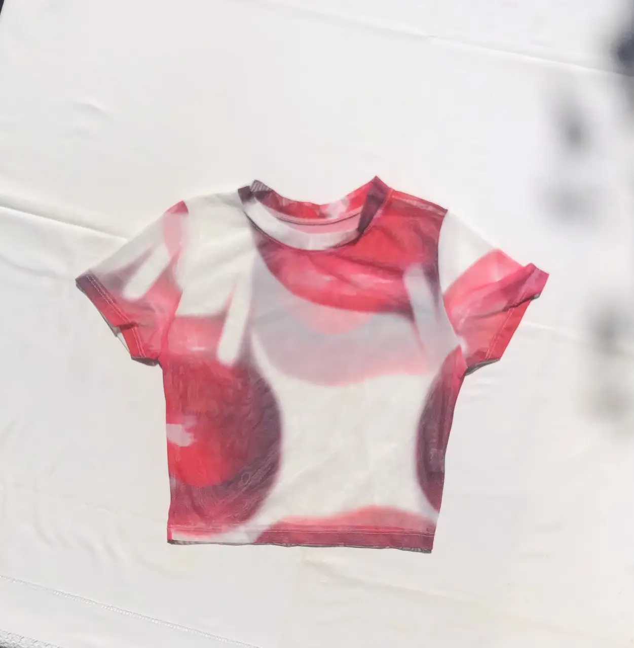 Top de red transparente con estampado abstracto en tonos rojos y blancos. Ideal para un look audaz y moderno.