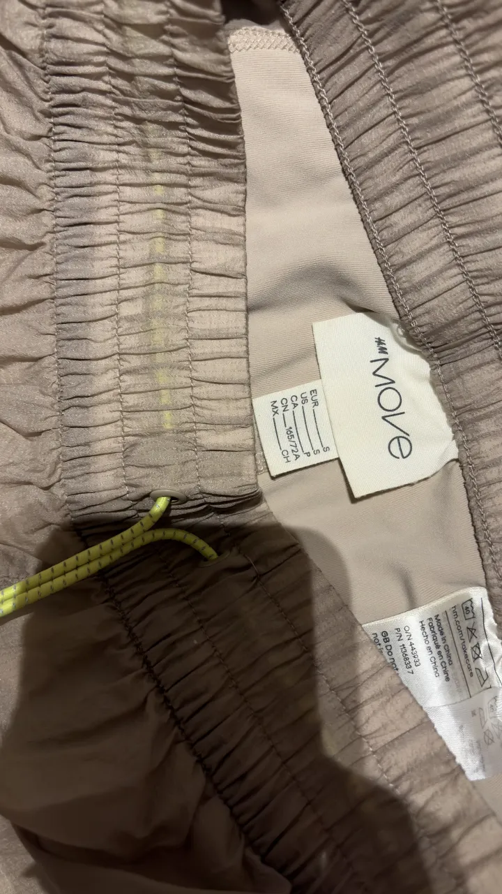 Shorts deportivos color tiza con cordón ajustable y detalles en amarillo flúo. Ideales para entrenar o para un look casual y cómodo.