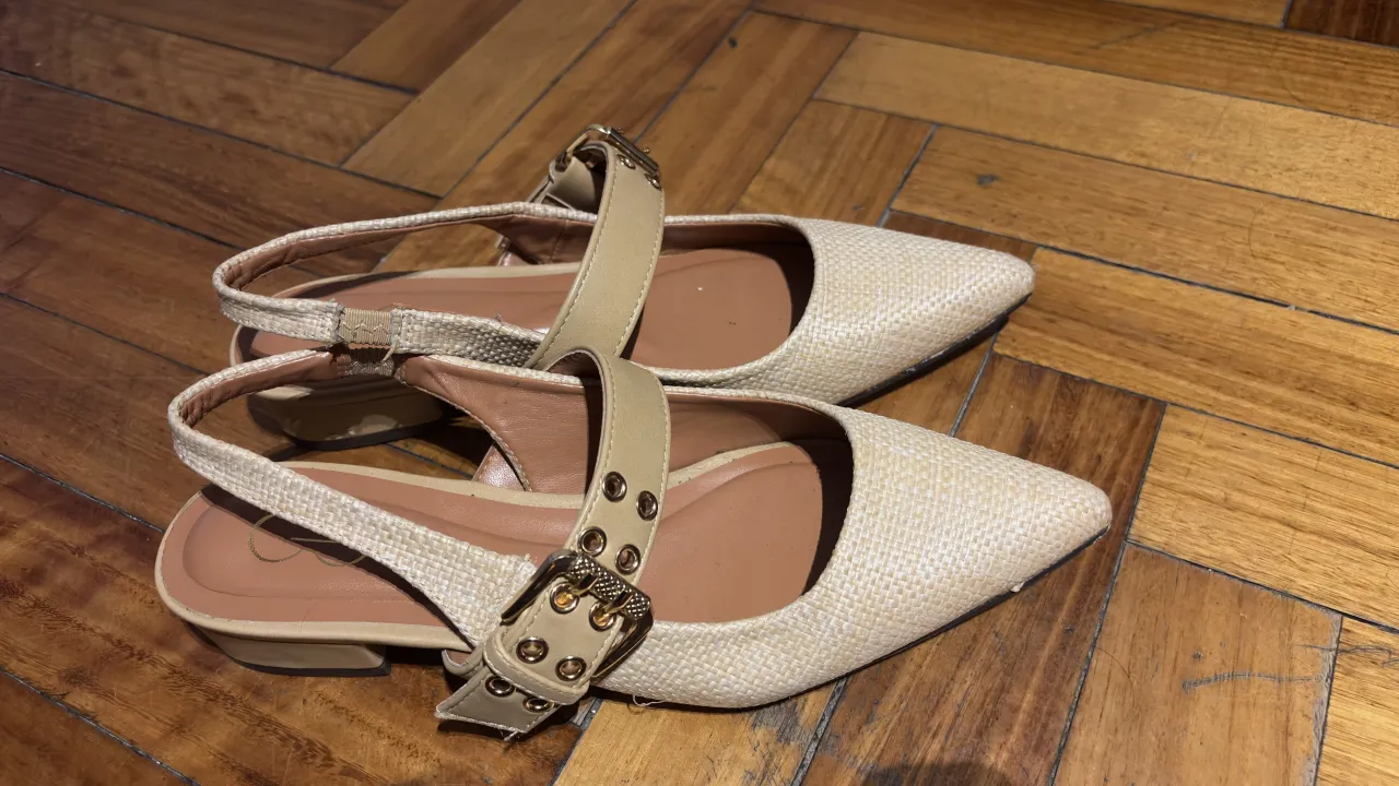Zapatos bajos de vestir color crudo, con tiras y hebillas doradas. Ideales para un look elegante y cómodo.