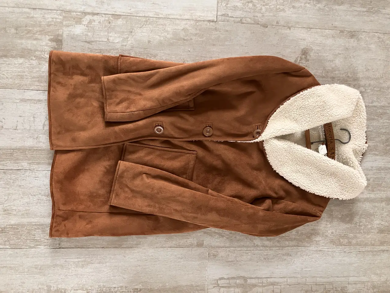 Tapado de gamuza marrón con cuello y puños de piel sintética blanca. Posee botones y bolsillos delanteros. Ideal para el invierno.