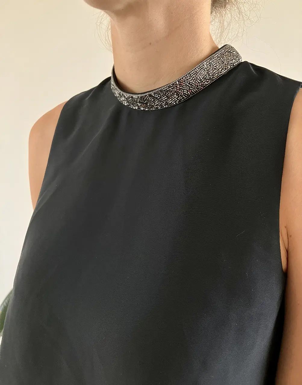 Top negro con cuello adornado con detalles plateados. Ideal para un look elegante y sofisticado.