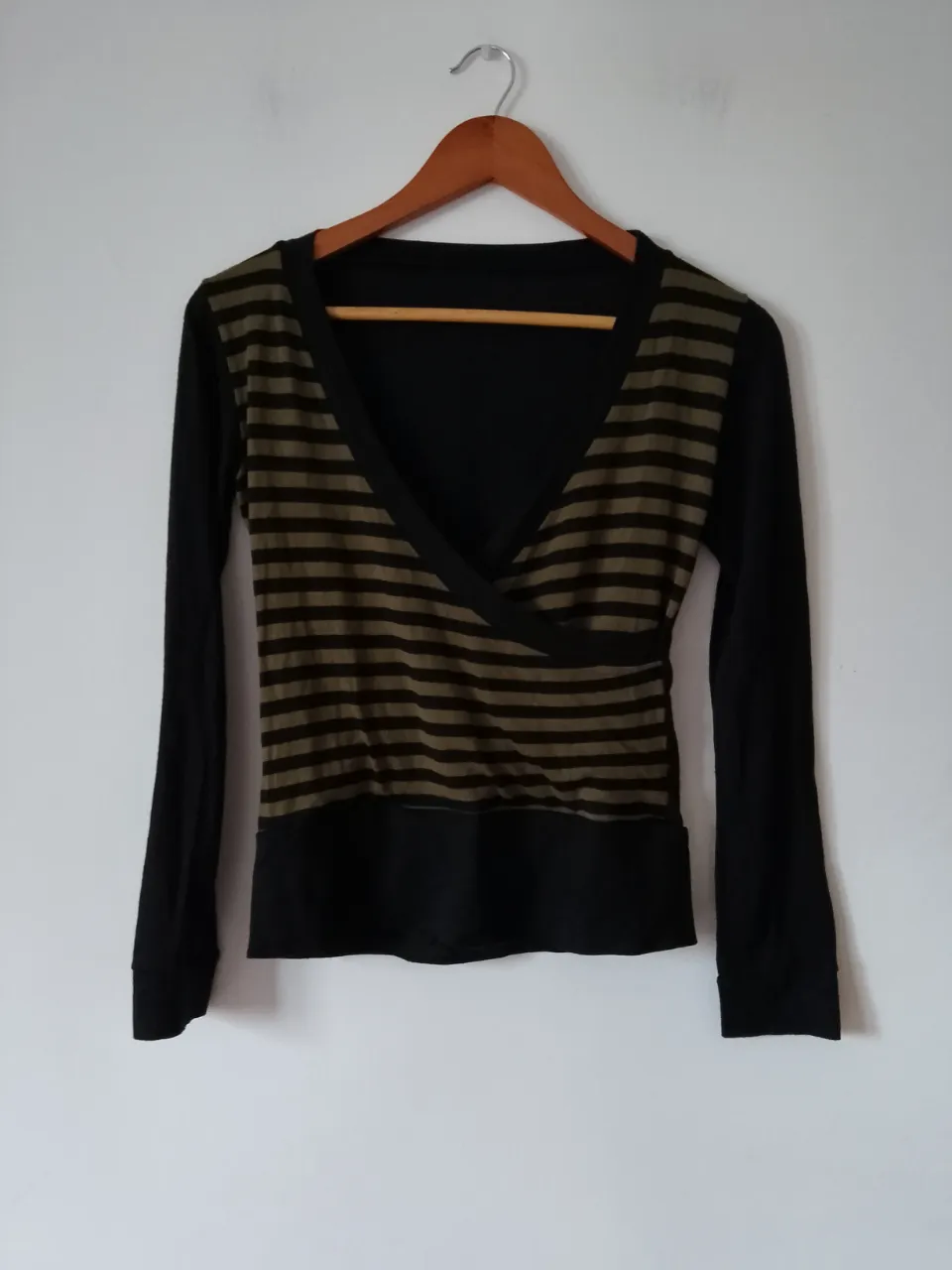Remera manga larga para mujer, con diseño cruzado en el frente y rayas horizontales en tonos verde oliva y negro. Ideal para un look casual y moderno.
