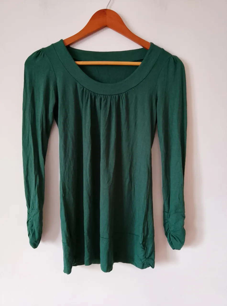 Blusa verde oscuro de manga larga con cuello redondo y detalles fruncidos. Ideal para un look elegante y versátil.