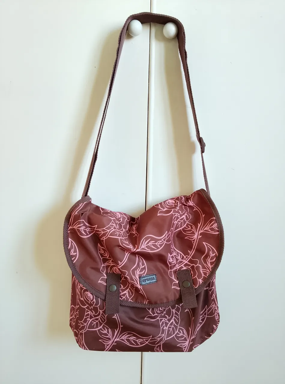 Bandolera marrón con estampado floral en rosa claro. Ideal para llevar tus esenciales con estilo y un toque vintage.
