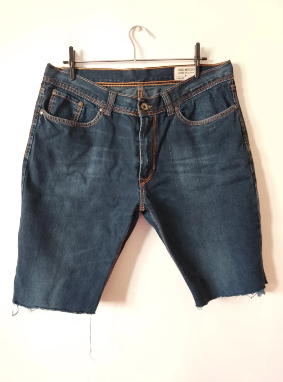 bermuda de jean azul de hombre, con corte a la rodilla y detalles de costura en naranja. Talla 36, en realidad largo, rigido