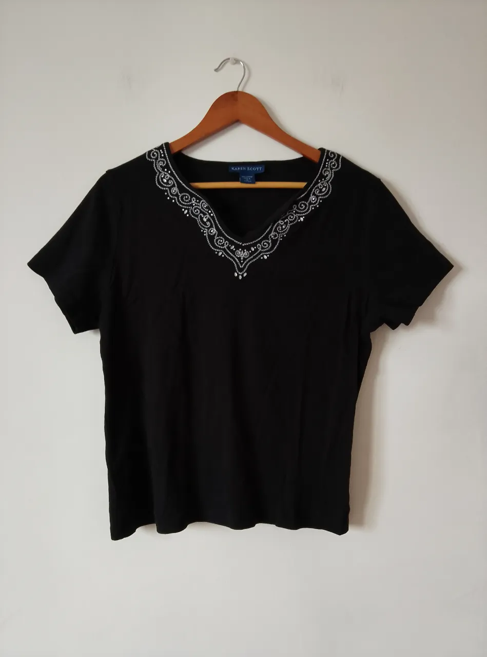Remera negra de manga corta con cuello en V adornado con detalles plateados. Marca Karen Scott, ideal para un look casual y elegante.