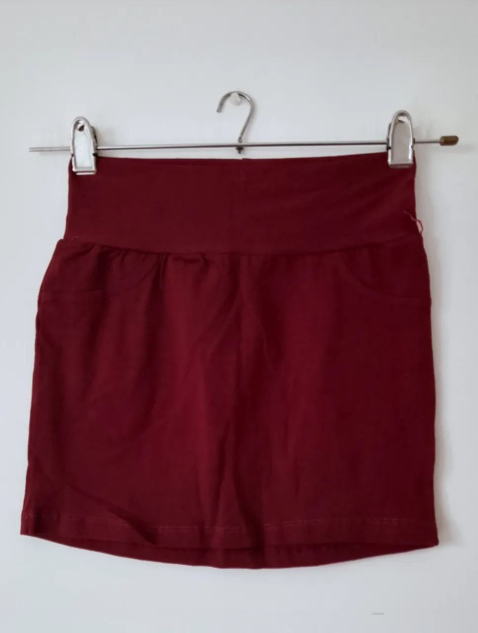 Minifalda de color bordó, tiro alto, con dos bolsillos delanteros. Ideal para un look casual y moderno.