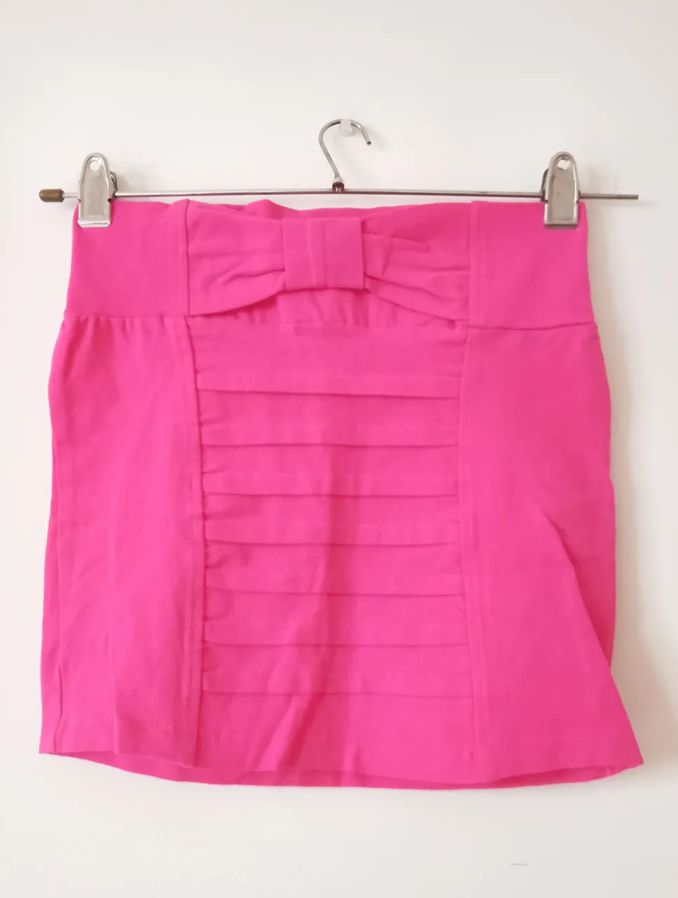 Minifalda rosa con detalle de moño y frunces en la parte delantera. Ideal para un look femenino y moderno.