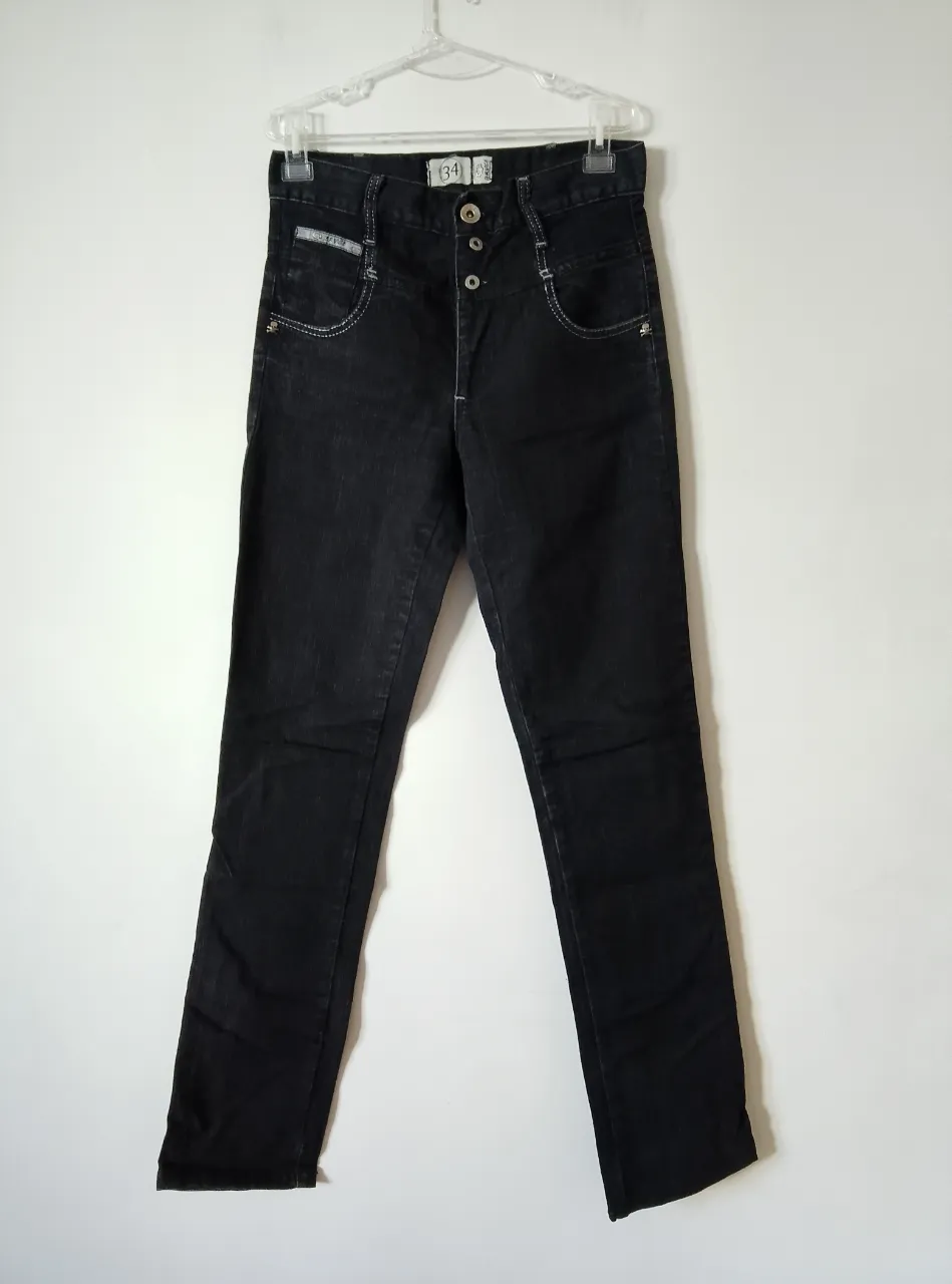 Jeans negro de corte recto con detalles de costura en blanco. Posee bolsillos delanteros y traseros, y cierre con botones. Ideal para un look casual y moderno.