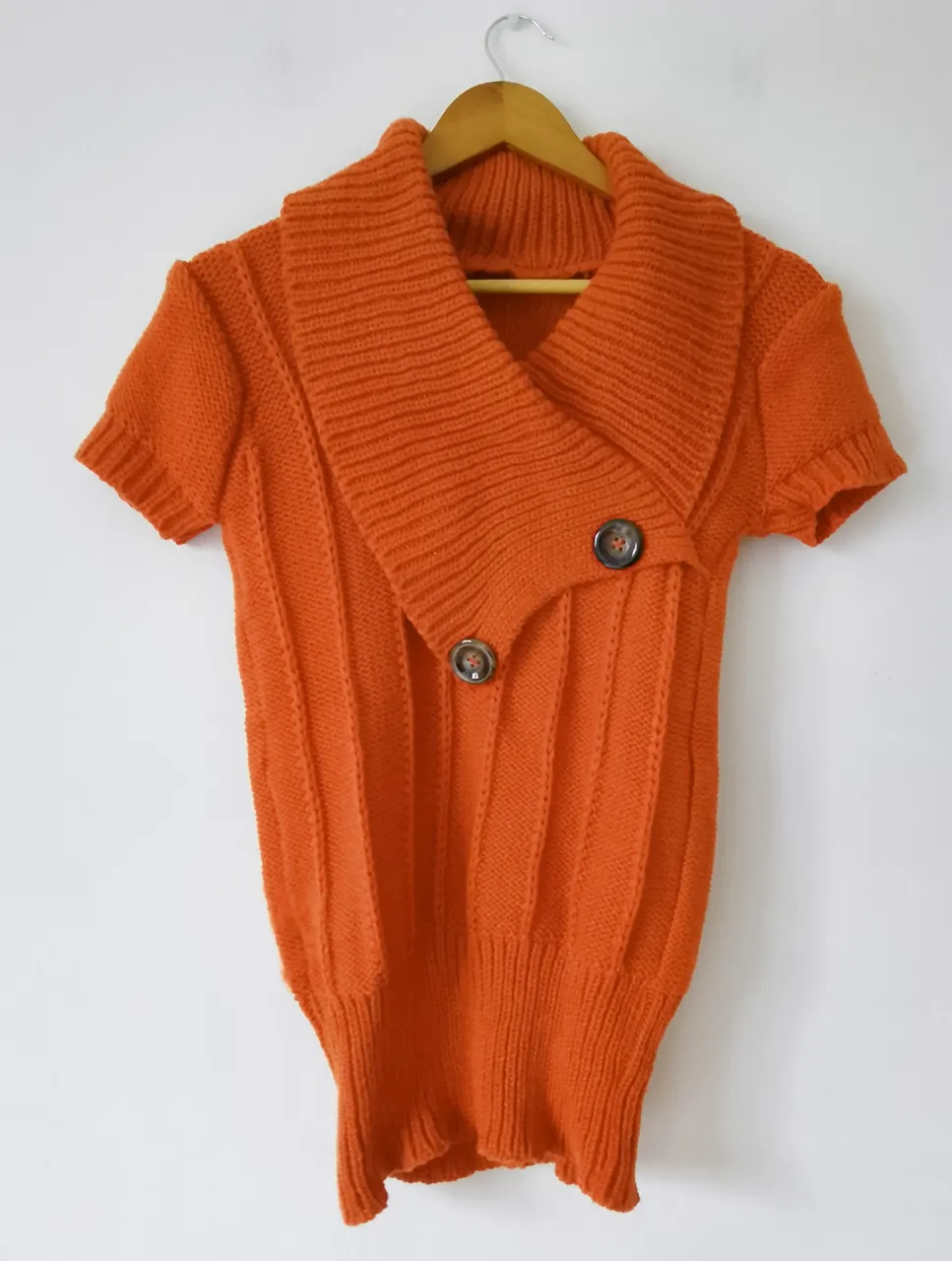 Sweater naranja con cuello solapa y botones. Manga corta. Ideal para un look moderno y abrigado.