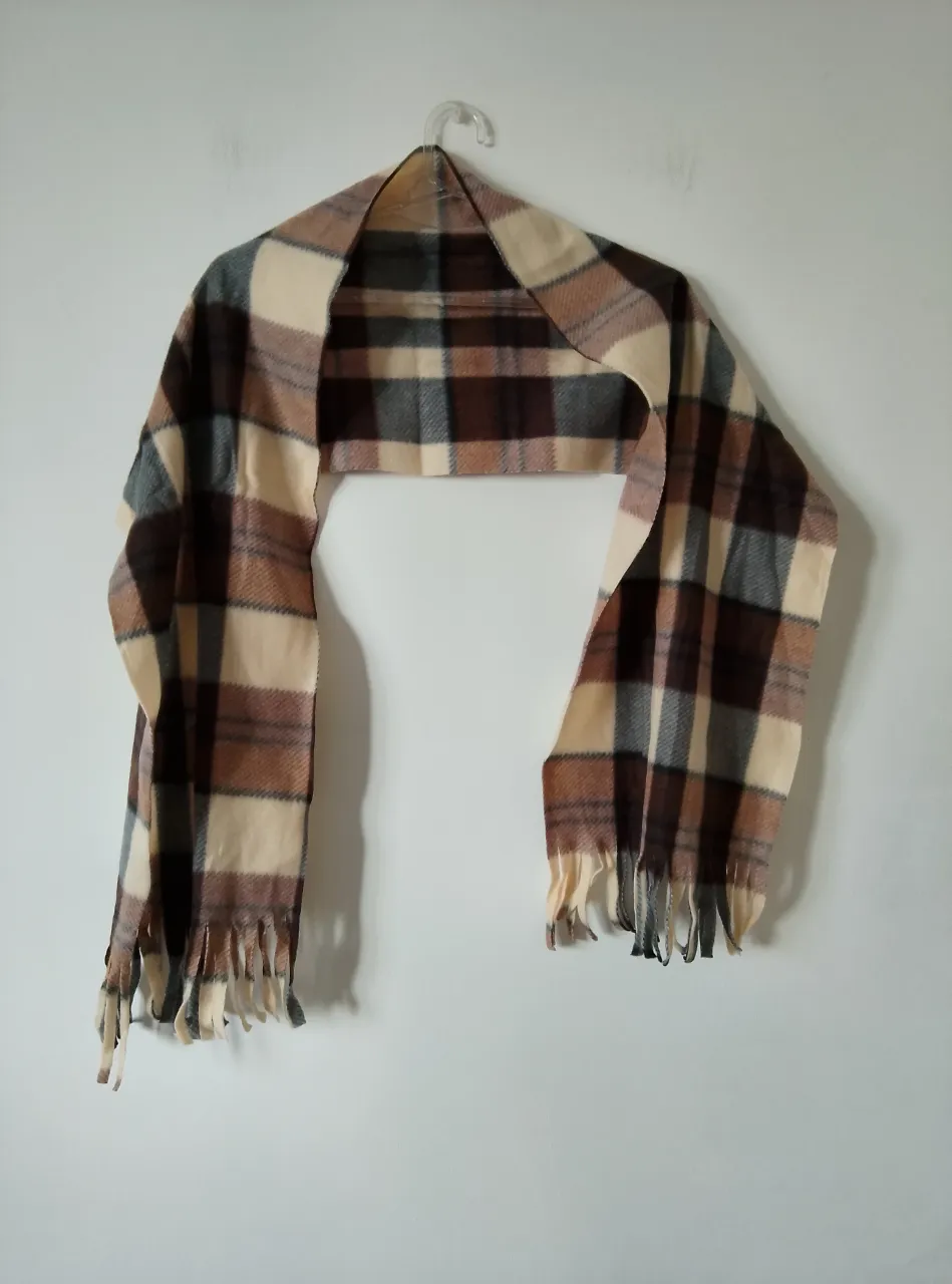 Bufanda a cuadros en tonos marrones y beige, ideal para el invierno. Un accesorio clásico y versátil para complementar cualquier look. Viene con su etiqueta
