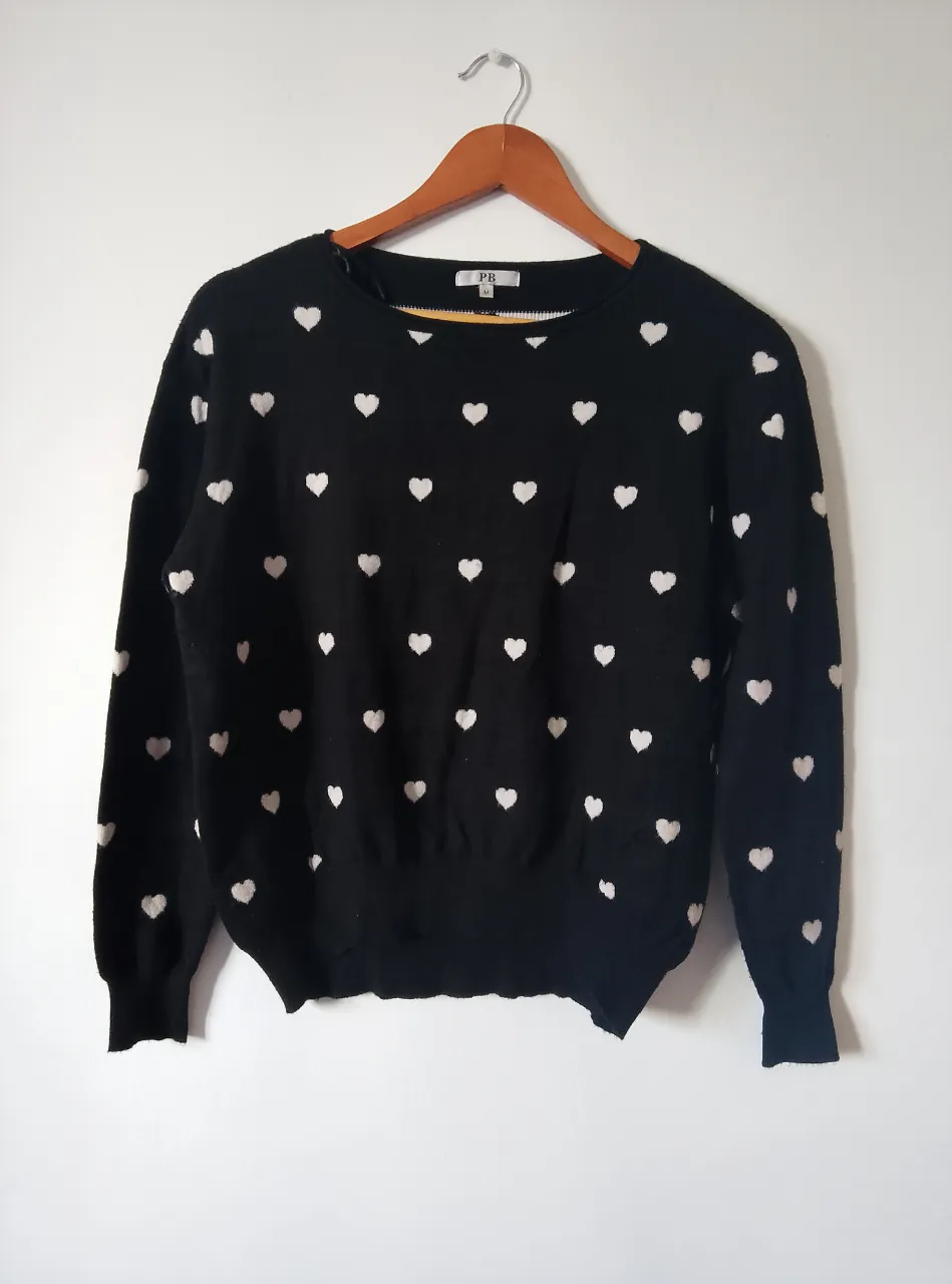 Sweater negro de mujer con diseño de corazones blancos. Ideal para un look casual y cómodo. Perfecto para el invierno.