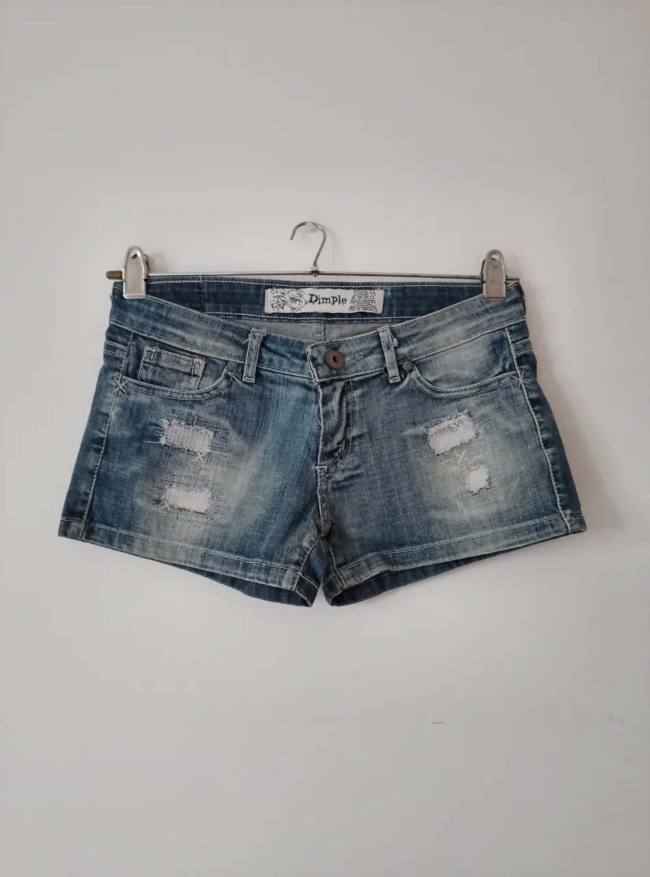 Short de jean Dimple azul con roturas y detalles desgastados. Tiro bajo, ideal para un look casual y moderno.