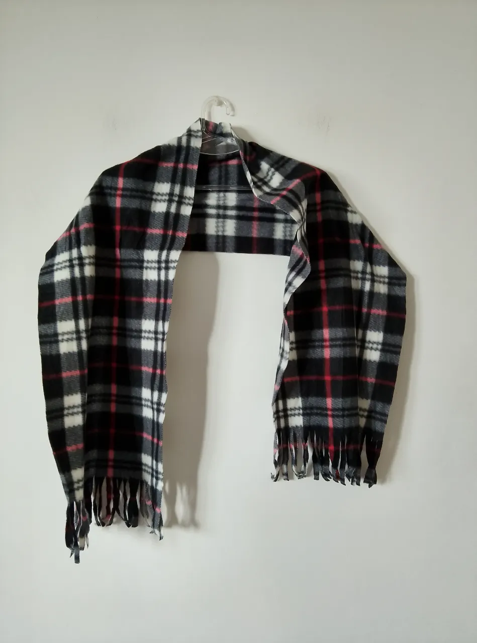 Bufanda a cuadros en blanco, negro y detalles en rojo. Ideal para el invierno, abrigada y con flecos en los extremos. Viene con su etiqueta