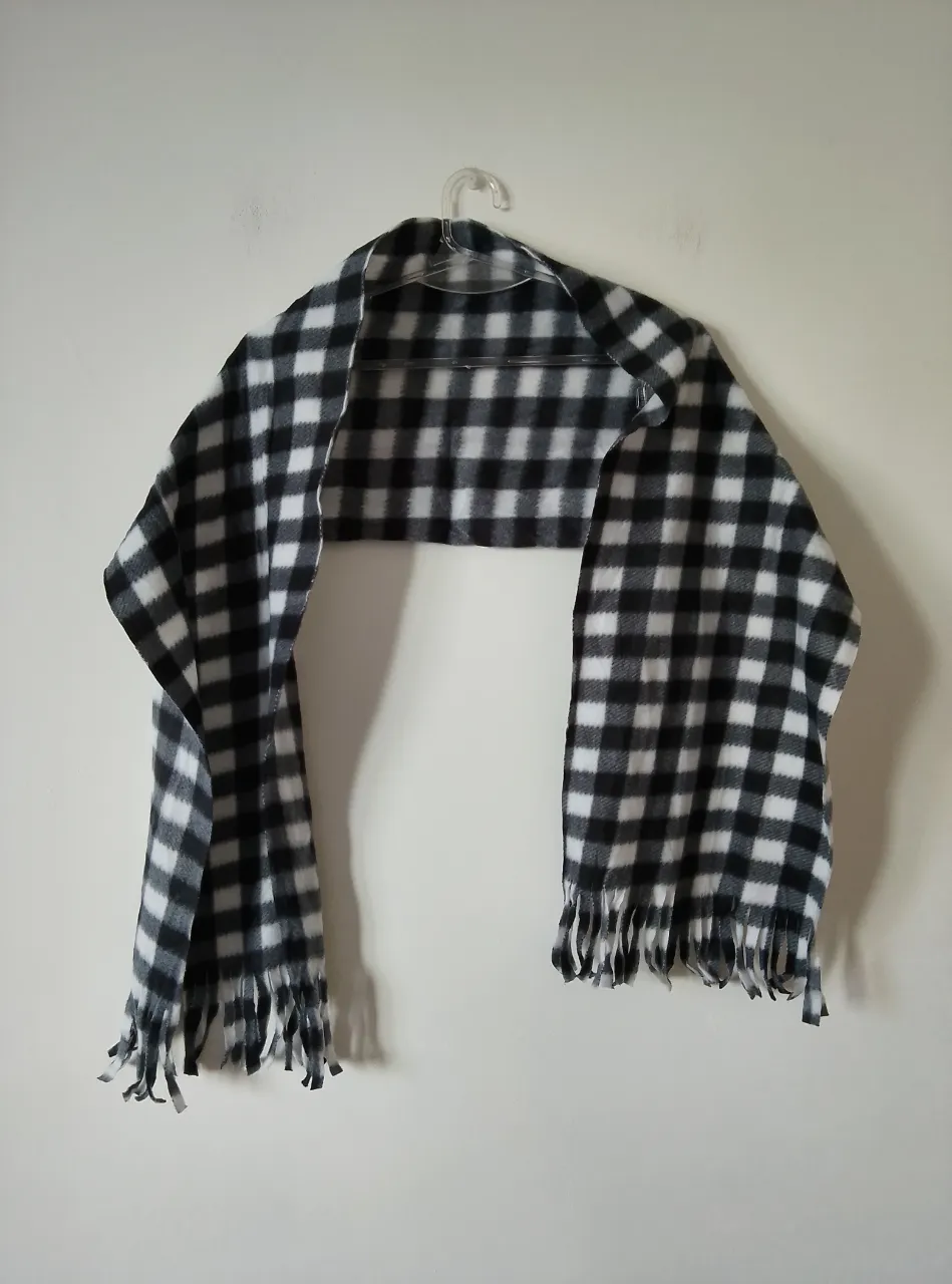Bufanda a cuadros en blanco y negro, ideal para el invierno. Con flecos en los extremos, perfecta para un look casual y abrigado. Viene con su etiqueta