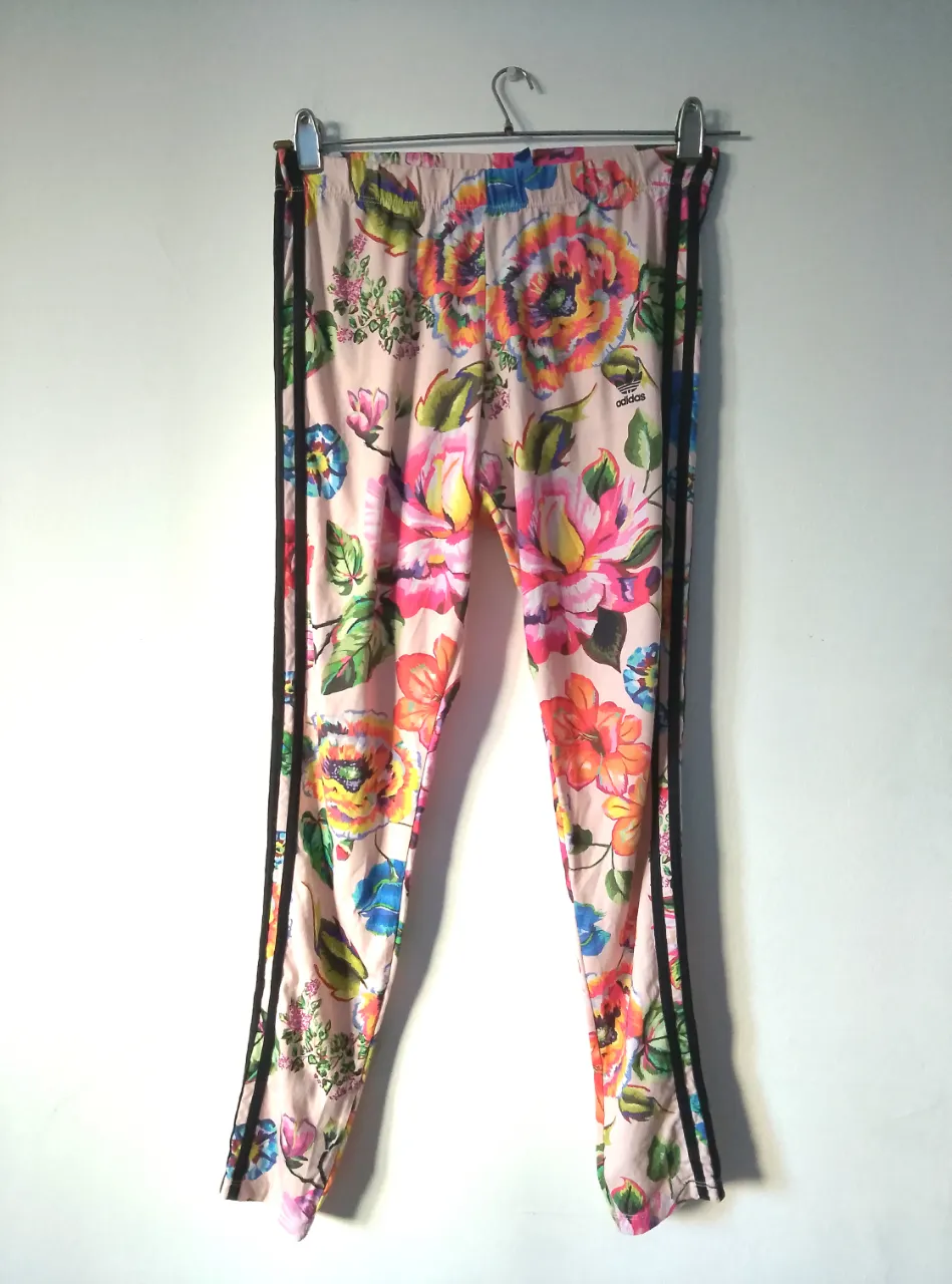 Pantalón deportivo Adidas con estampado floral. Talle M. Confeccionado en poliéster y elastano. Ideal para un look casual y cómodo.