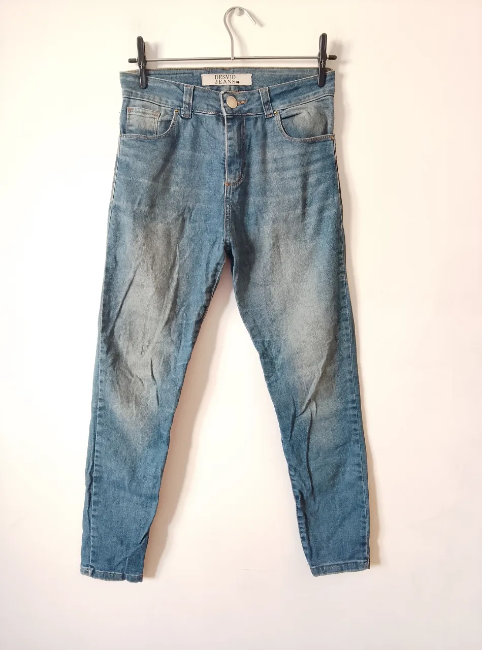 Pantalones de jean chupín rígido marca Desvío Jeans, talle 28. Con 5 bolsillos en total. Material: 98% algodón y 2% spandex
Medidas: 91cm largo delantero, 26,5cm tiro delantero, 24cm botamanga,  88cm cadera, 77cm cintura. detalle de desgastado en el logo de atras