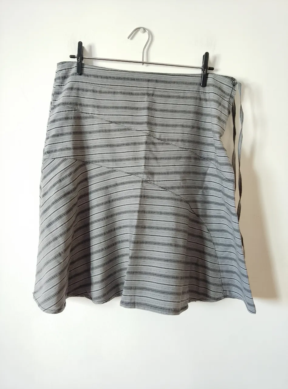 Pollera larga a rayas grises y negras, con cierre lateral y lazos para ajustar. Pollera a rayas grises de tela rígida de poliéster y algodón talle 4. Con cierre lateral y dos tiras decorativas.
Medidas: 88cm cintura x 55,5cm largo