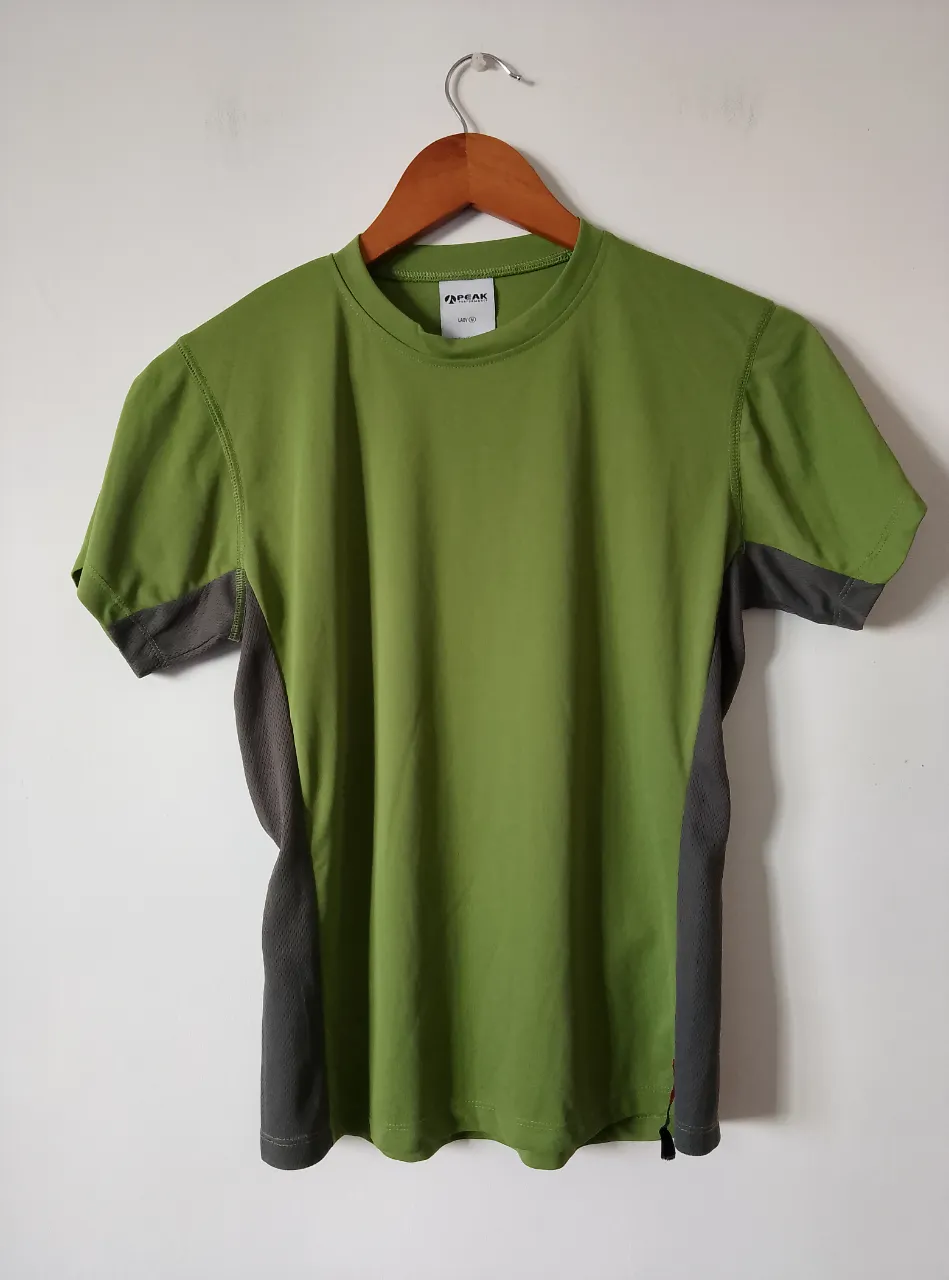 Remera deportiva de mujer, color verde con detalles en gris. Ideal para actividades físicas.