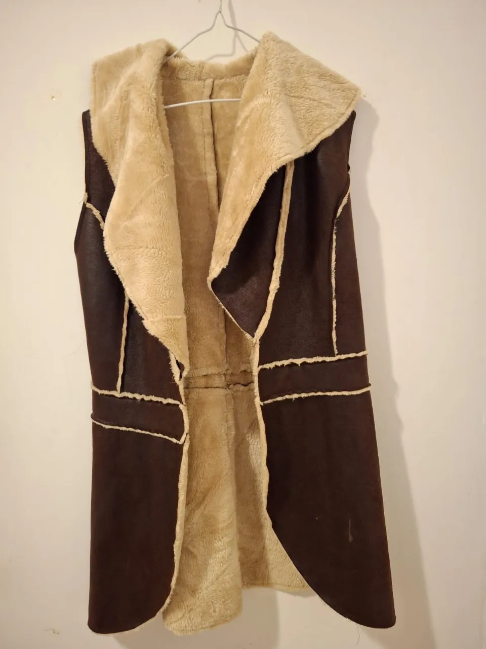 Chaleco largo de mujer, con interior de piel sintética color crudo y exterior símil cuero marrón. Ideal para el invierno, abrigo y estilo en una sola prenda.