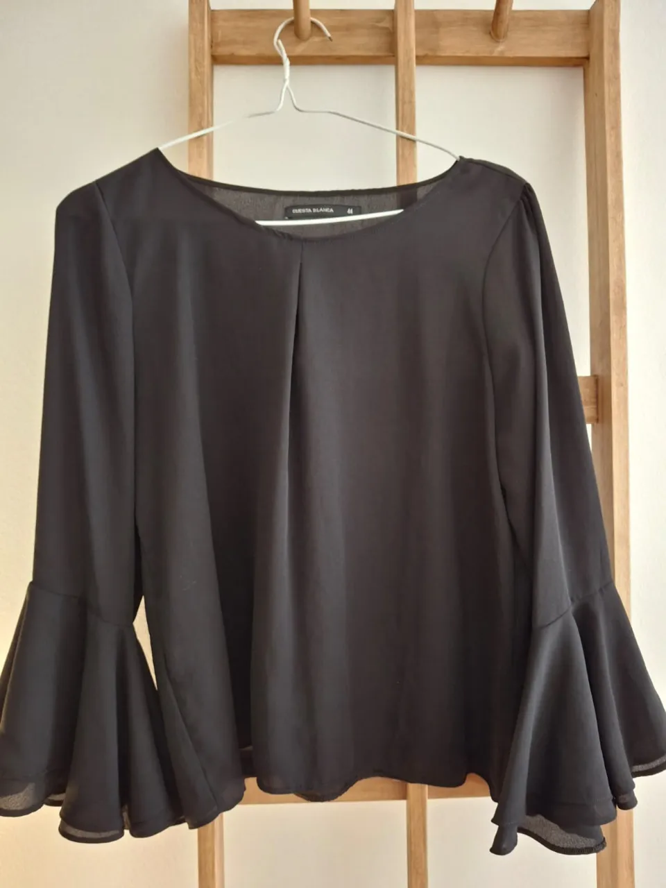Blusa negra con mangas largas acampanadas, ideal para un look elegante y sofisticado. Perfecta para combinar con pantalones de vestir o faldas.