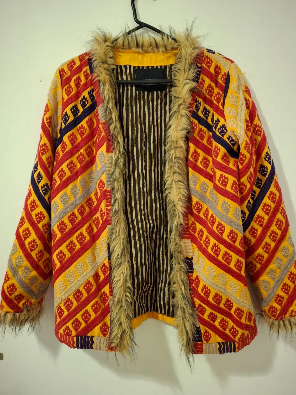 Saco Rapsodia con diseño artesanal, con detalles en rojo, amarillo y azul. Posee detalles de piel en el cuello y puños. Ideal para un look vintage y abrigado. 
